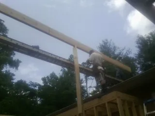 Carpenter setting a ridge beam over a new addition frame in Bakersville