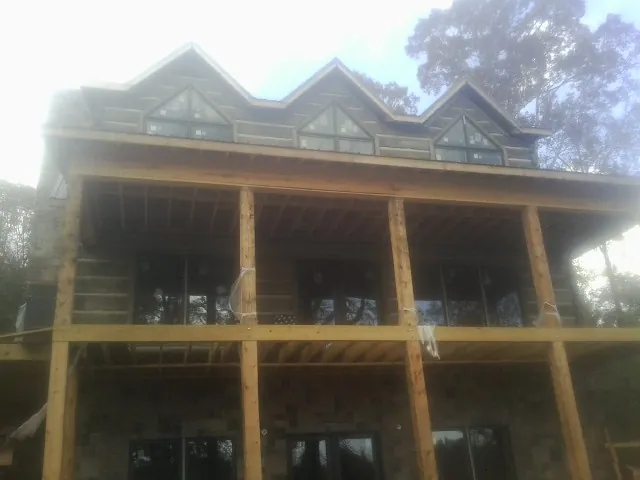 Dormers and porch framing on a large log home under construction — Roof Coating work by our crew in Bakersville