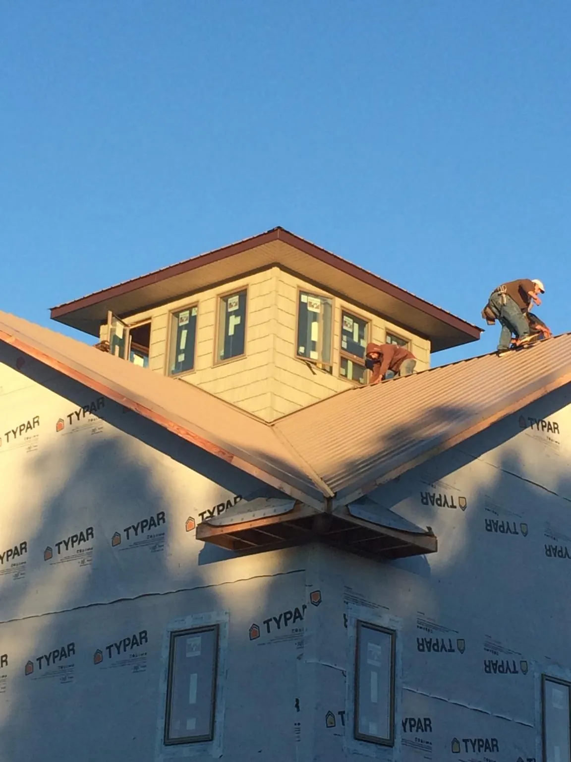 Roofers working around a rooftop cupola on a new metal roof at sunset — Roof Waterproofing in Bakersville by Roofing Brothers